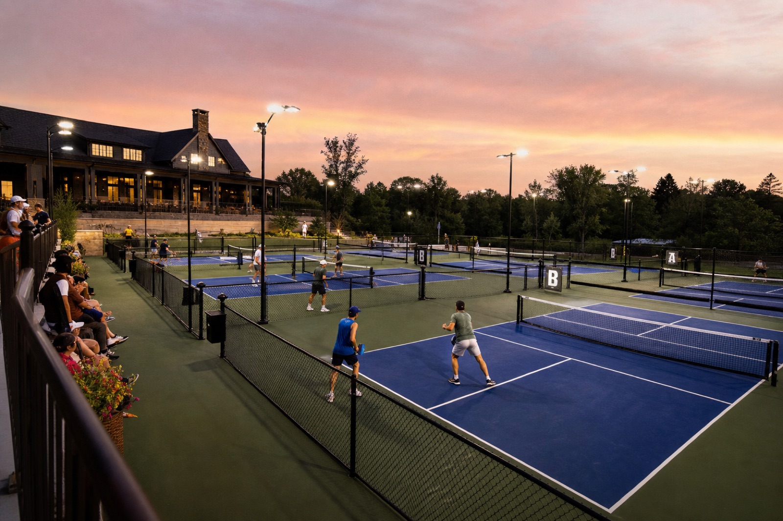 Private multi-court pickleball facility in use at dusk with spectators and lighting