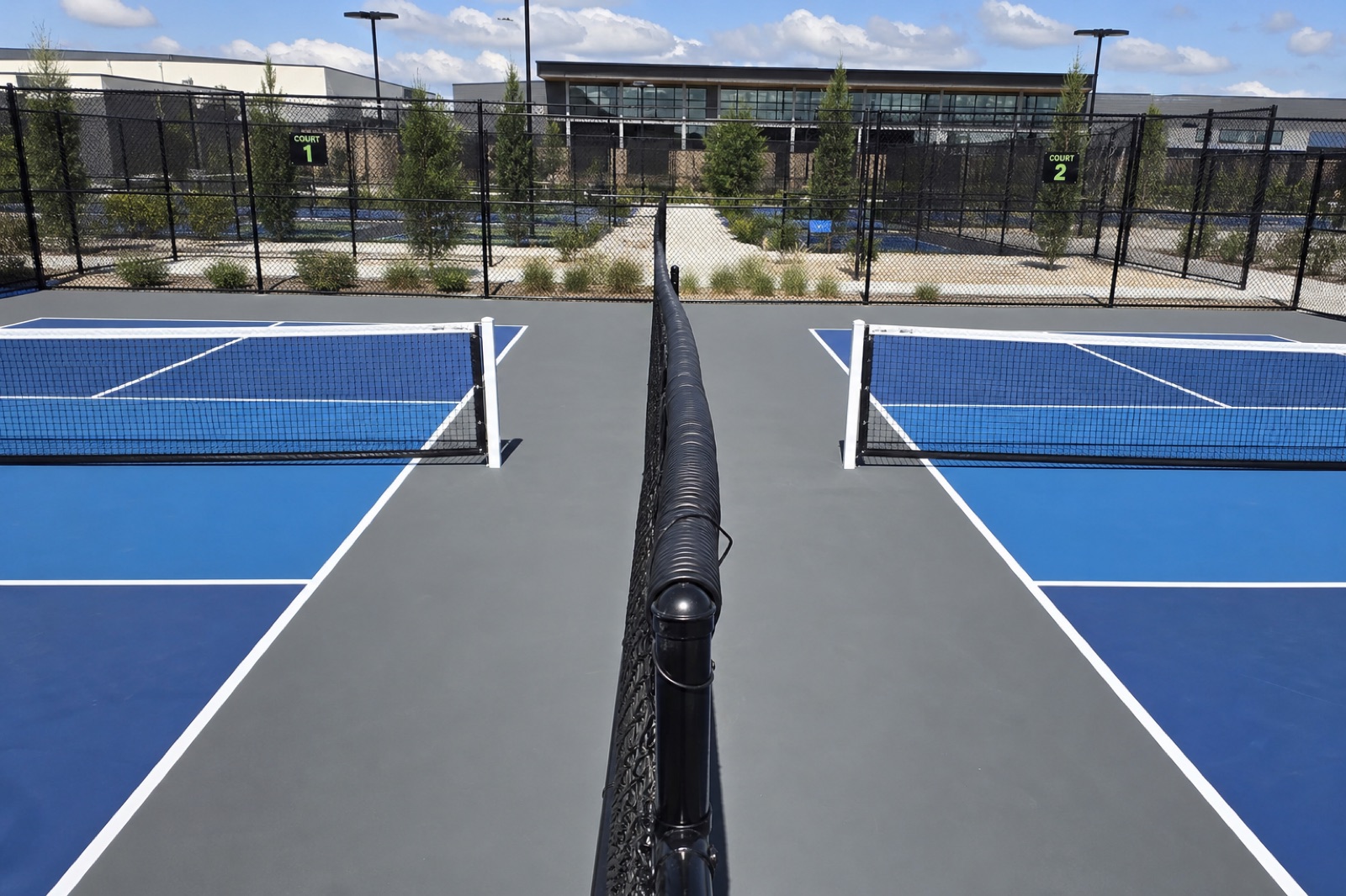 Divider fencing separating adjoining pickleball courts