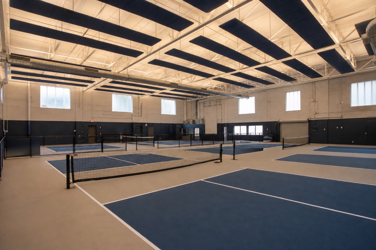 Indoor pickleball courts with overhead lighting